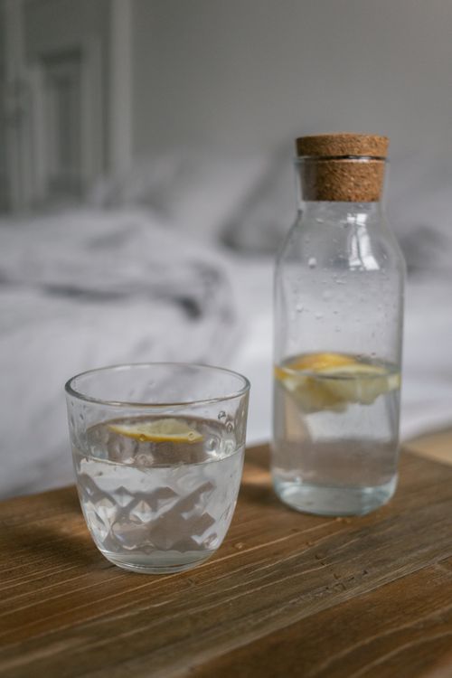 Free Close-up of a glass and bottle with lemon water on a wooden surface, perfect for health and lifestyle concepts. Stock Photo