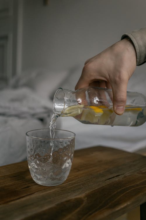 Person Pouring Liquid on Clear Glass