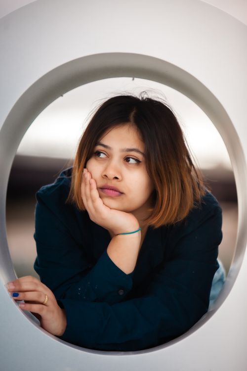 Free A woman with short hair rests her chin on her hand, gazing thoughtfully. Stock Photo