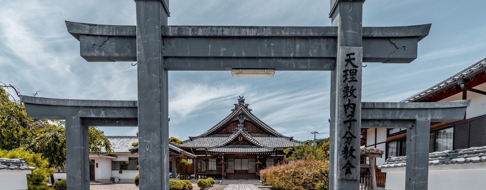 Peaceful view of a traditional Japanese temple entrance with a Torii gate.