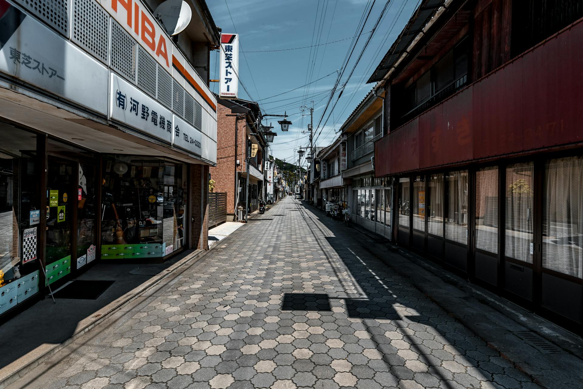 Quiet street in Japan with traditional storefronts and shops during the day.