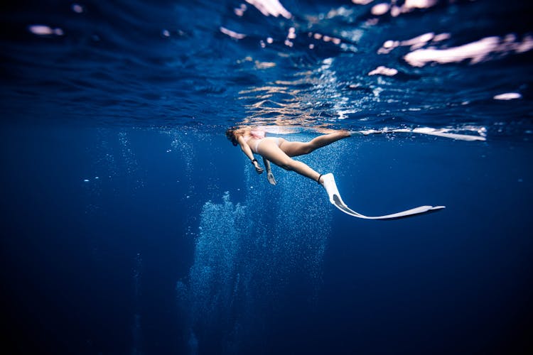 Slim Female Diver In Flippers Swimming In Blue Sea