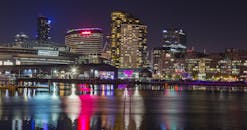 现代城市景观的夜间视图展现了充满活力的城市灯光，明亮的建筑和水面的倒影交相辉映