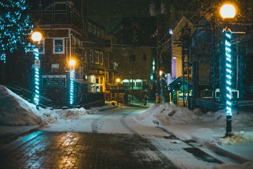Free Captivating winter city street scene during snowfall with glowing lights. Stock Photo