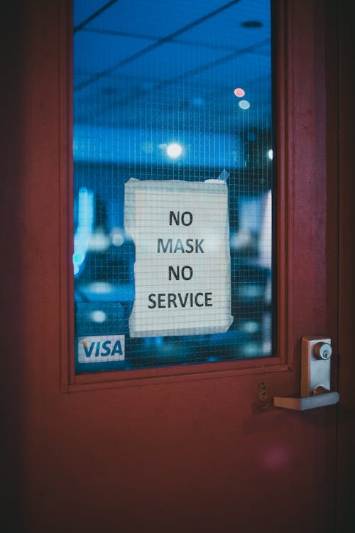 Free Safety sign on piece of paper on window of closed door of cafe displaying message No Mask No Service for preventing spreading COVID 19 Stock Photo