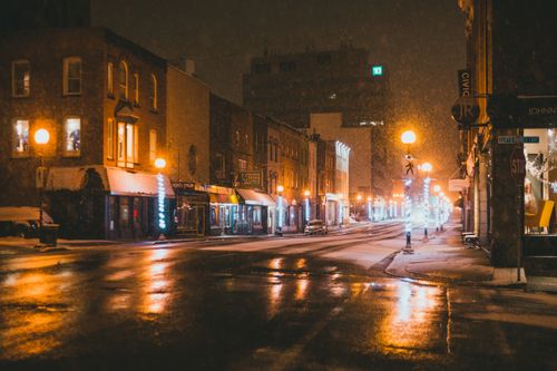 Free Empty asphalt road between modern buildings with glowing lights and signboards on snowy night in winter Stock Photo