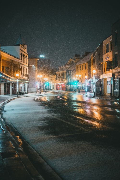 Free Buildings and street lights near empty asphalt road under dark sky on snowy night in winter Stock Photo