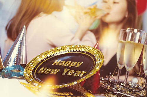 New Year party supplies on table with women drinking champagne