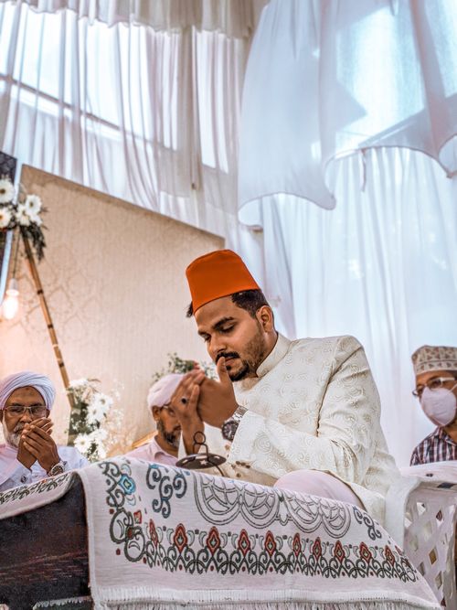 Free A bearded man in traditional attire solemnly praying during a ceremonial event. Stock Photo