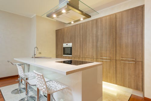 Interior of contemporary illuminated kitchen with minimalist styled furniture and built in appliances in spacious apartment