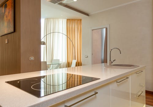 Built in stove and sink with chrome faucet on counter in modern kitchen with dining area in spacious apartment