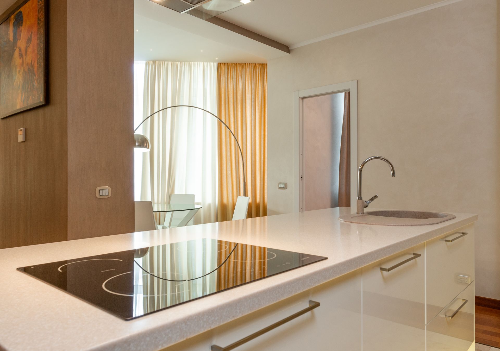 Built in stove and sink with chrome faucet on counter in modern kitchen with dining area in spacious apartment