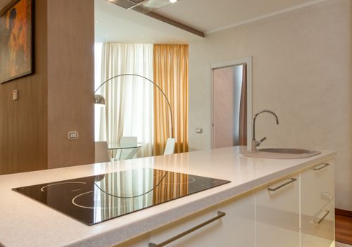 Free Built in stove and sink with chrome faucet on counter in modern kitchen with dining area in spacious apartment Stock Photo