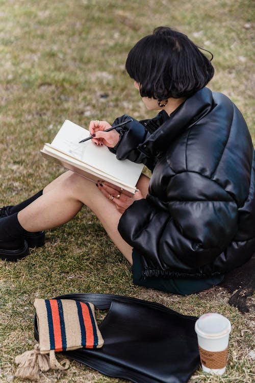 Unrecognizable woman writing in copybook in park