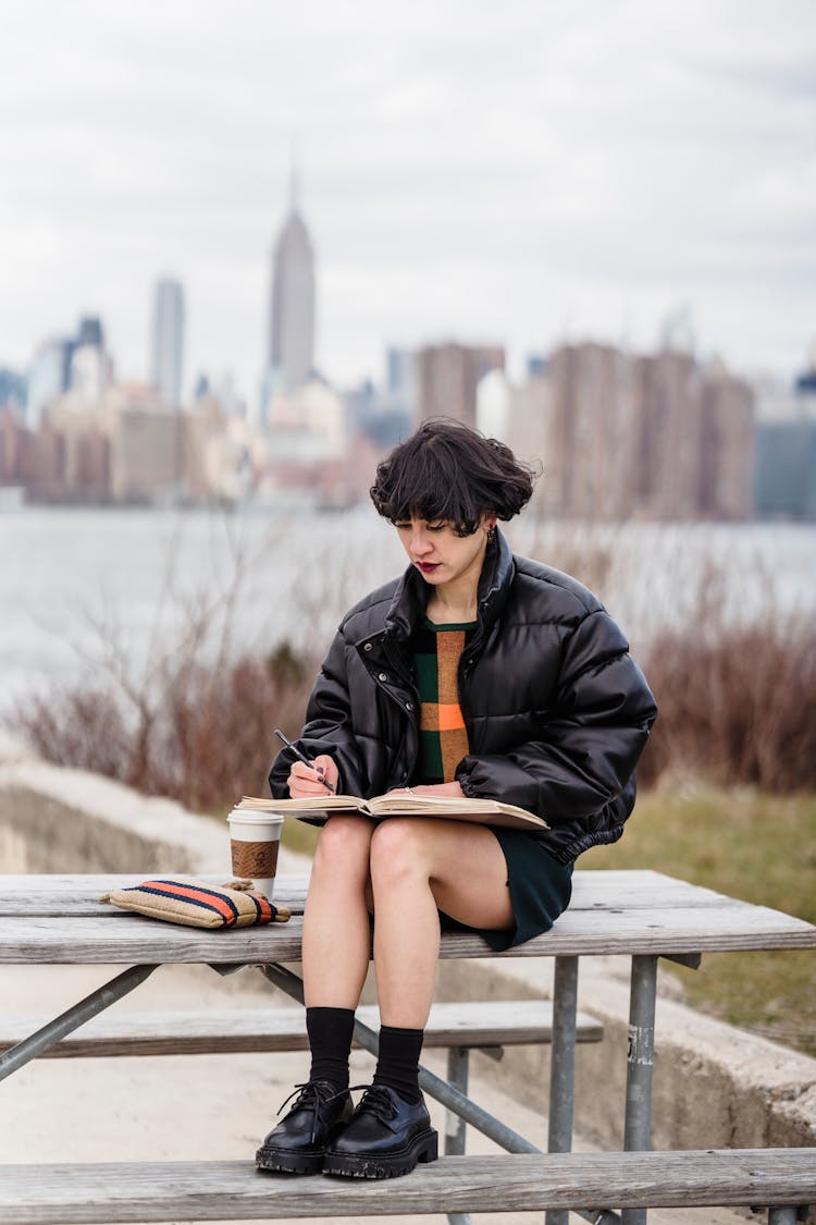 Serious Asian Woman Writing In Workbook Near Sea