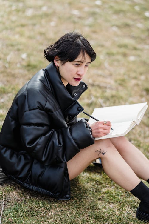 Concentrated Asian woman studying on lawn