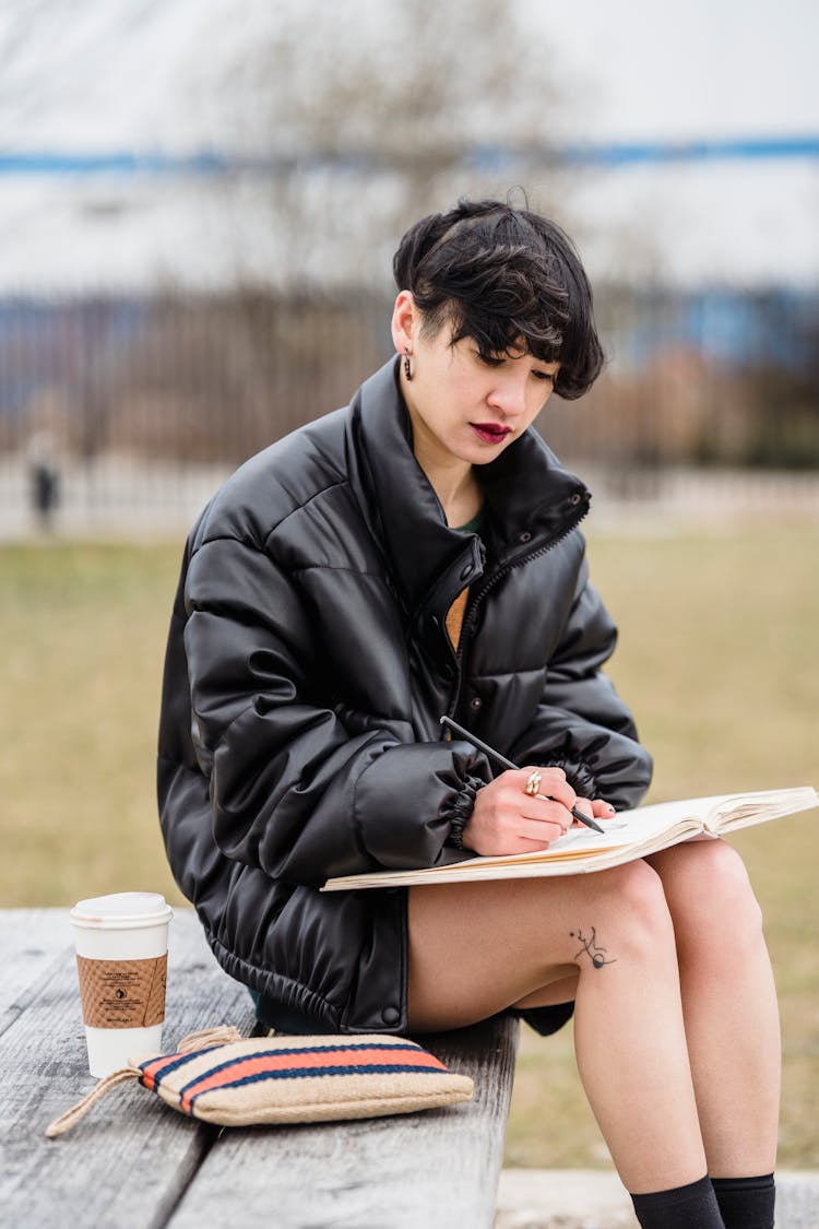 Cool Asian Student Writing In Copybook On Urban Bench