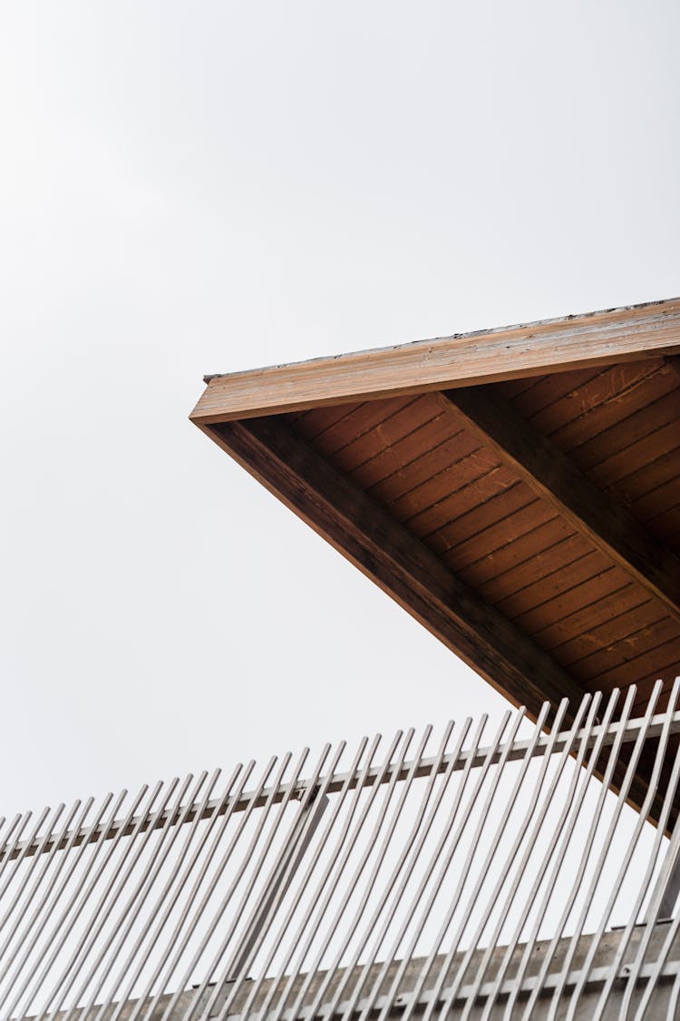 House Roof Above Fence Under White Sky