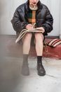 Crop trendy student with copybook studying on street