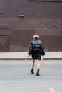 Unrecognizable cool woman in jacket crossing road in town