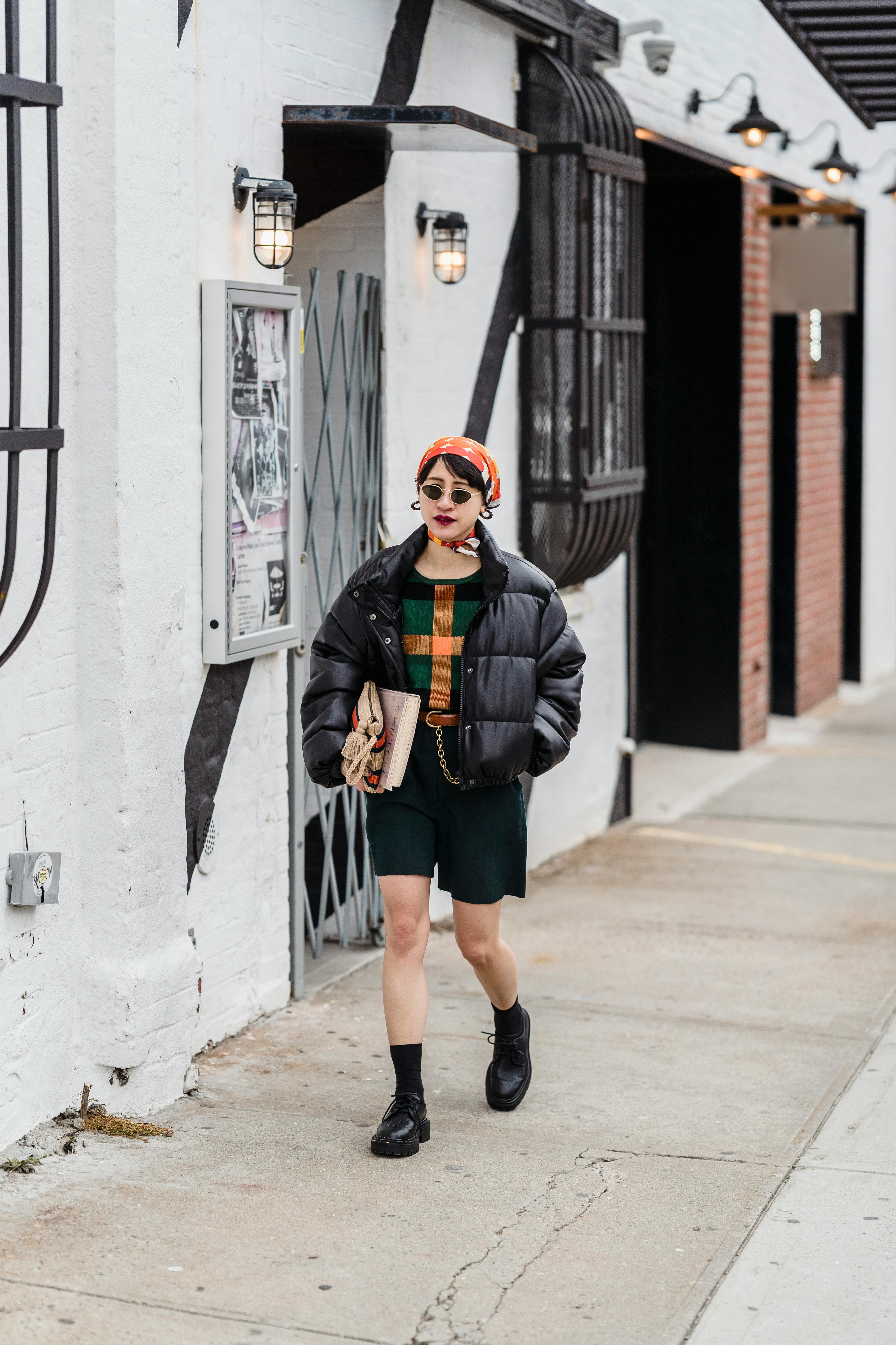 trendy ethnic student strolling on footpath in town