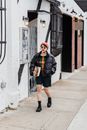 Trendy ethnic student strolling on footpath in town