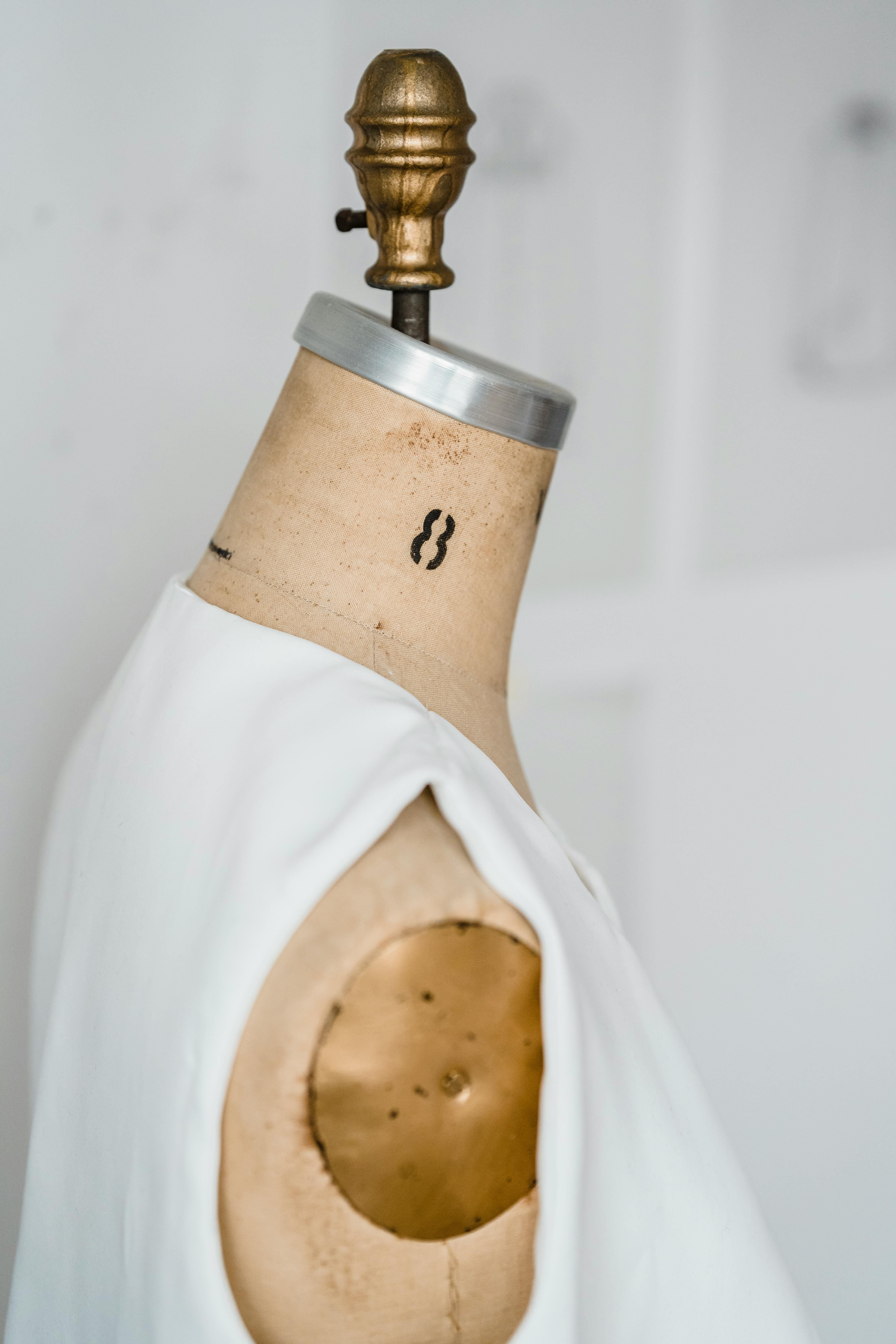 An unfinished white garment rests on a mannequin in a bright atelier