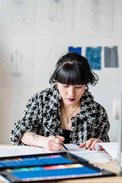 Pensive Asian designer sketching in atelier