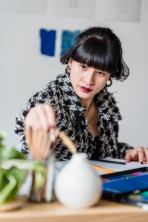 Serious Asian woman taking pencils at table