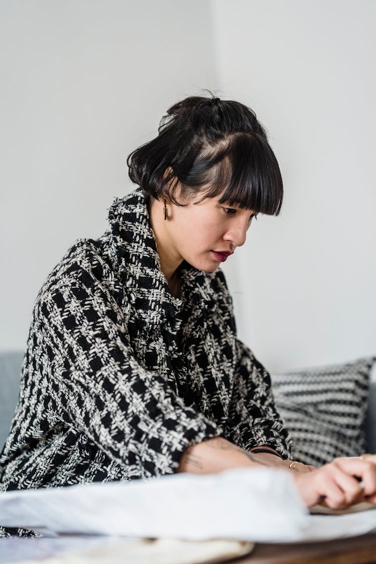 Asian Designer With Paper At Table In Room