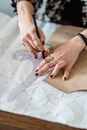High angle of crop anonymous female dressmaker tracing with pencil on paper with carton template and curved ruler in workspace