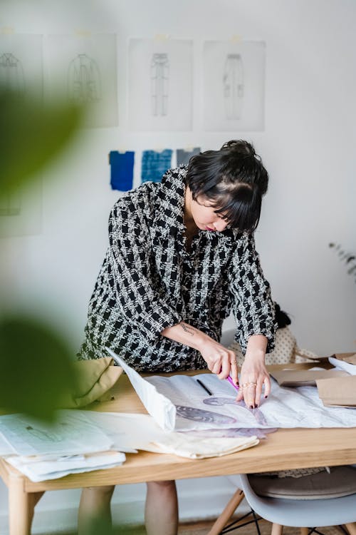 Attentive Asian dressmaker tracing on paper with sewing ruler