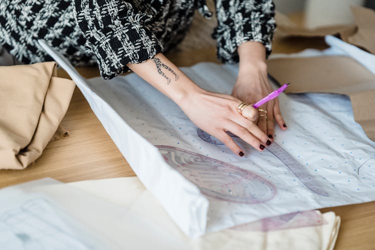 Faceless Seamstress With Sewing Rulers And Paper At Desk