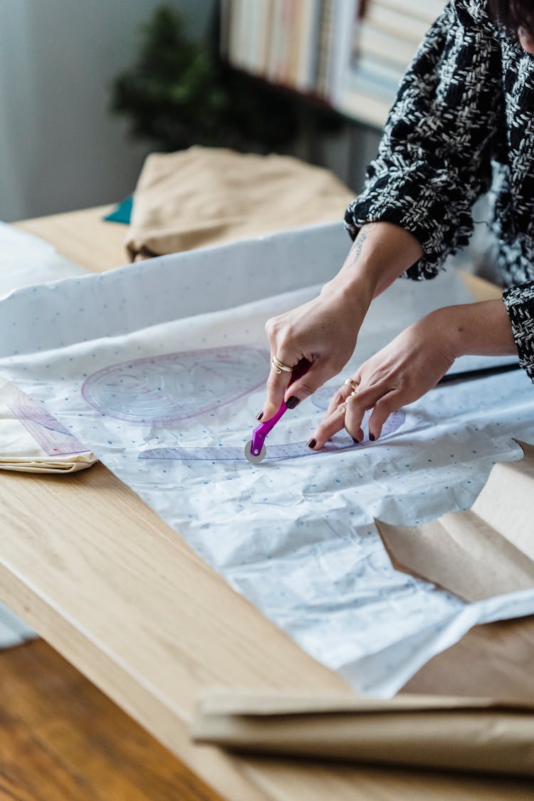 Crop Tailor With Sewing Ruler Cutting Paper In Workroom