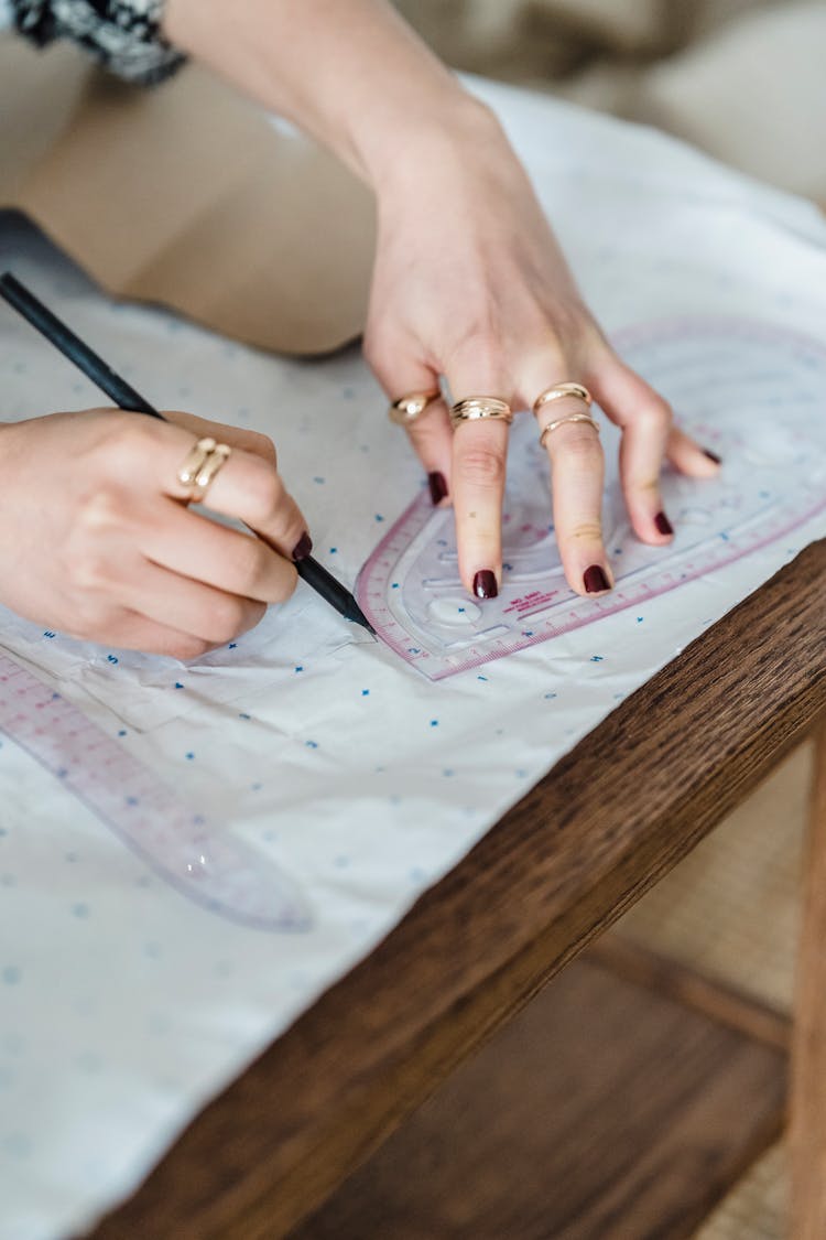 Crop Seamstress Tracing On Paper With Sewing Ruler In Workshop