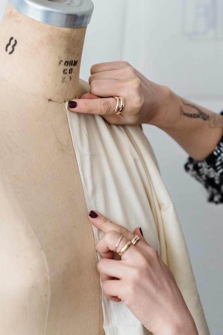 Crop Dressmaker Measuring Fabric On Mannequin In Workroom