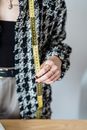 Crop tailor showing measuring tape at table in workroom