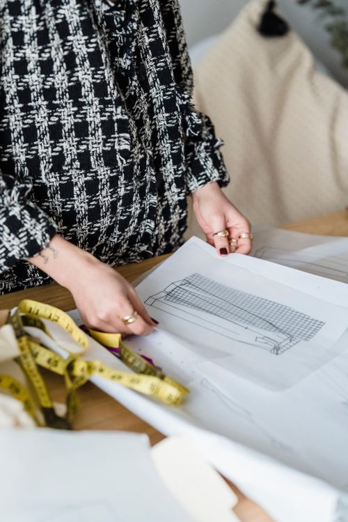 Free A fashion designer working on sketches and measuring tape in a creative studio. Stock Photo