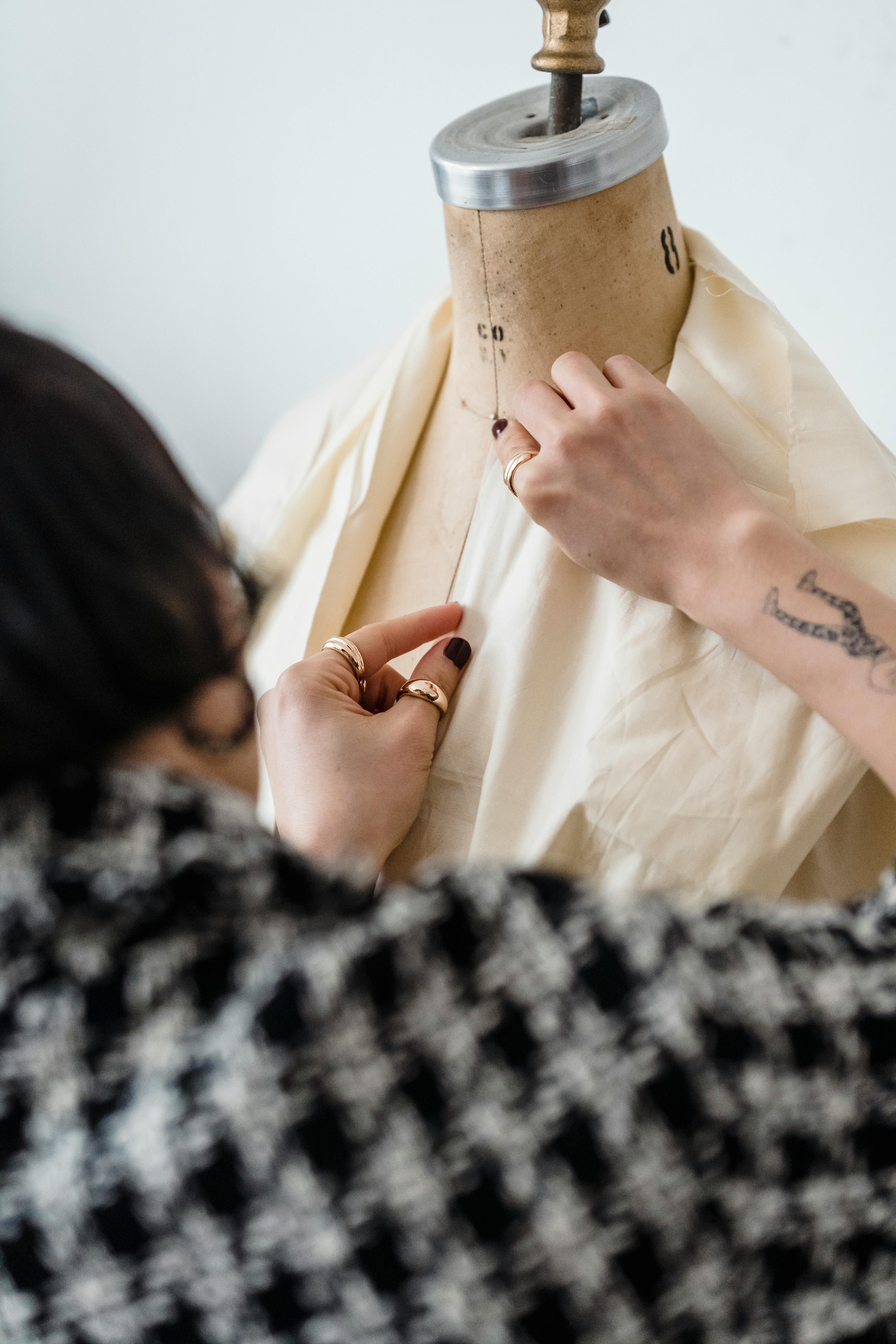 unrecognizable dressmaker working with garment on mannequin