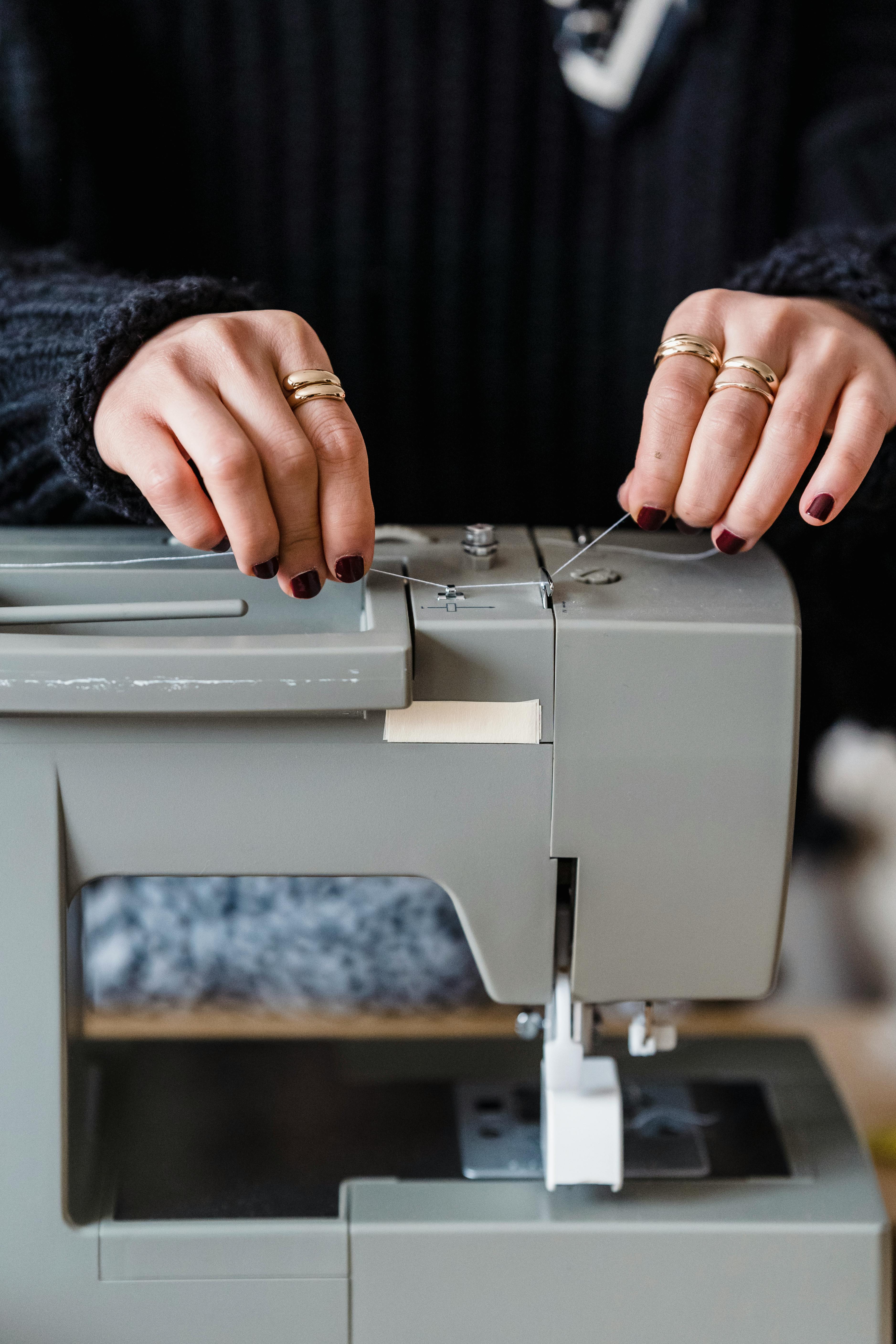 unrecognizable seamstress threading sewing machine