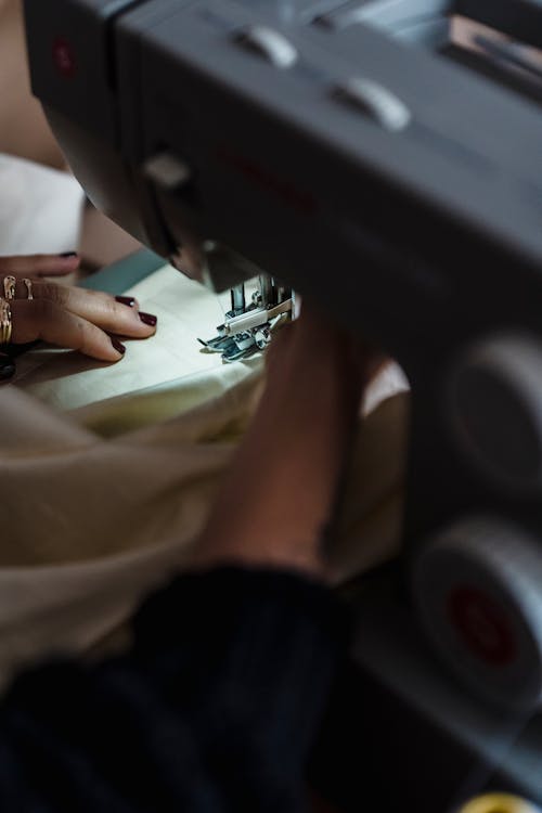 Faceless seamstress sewing white textile