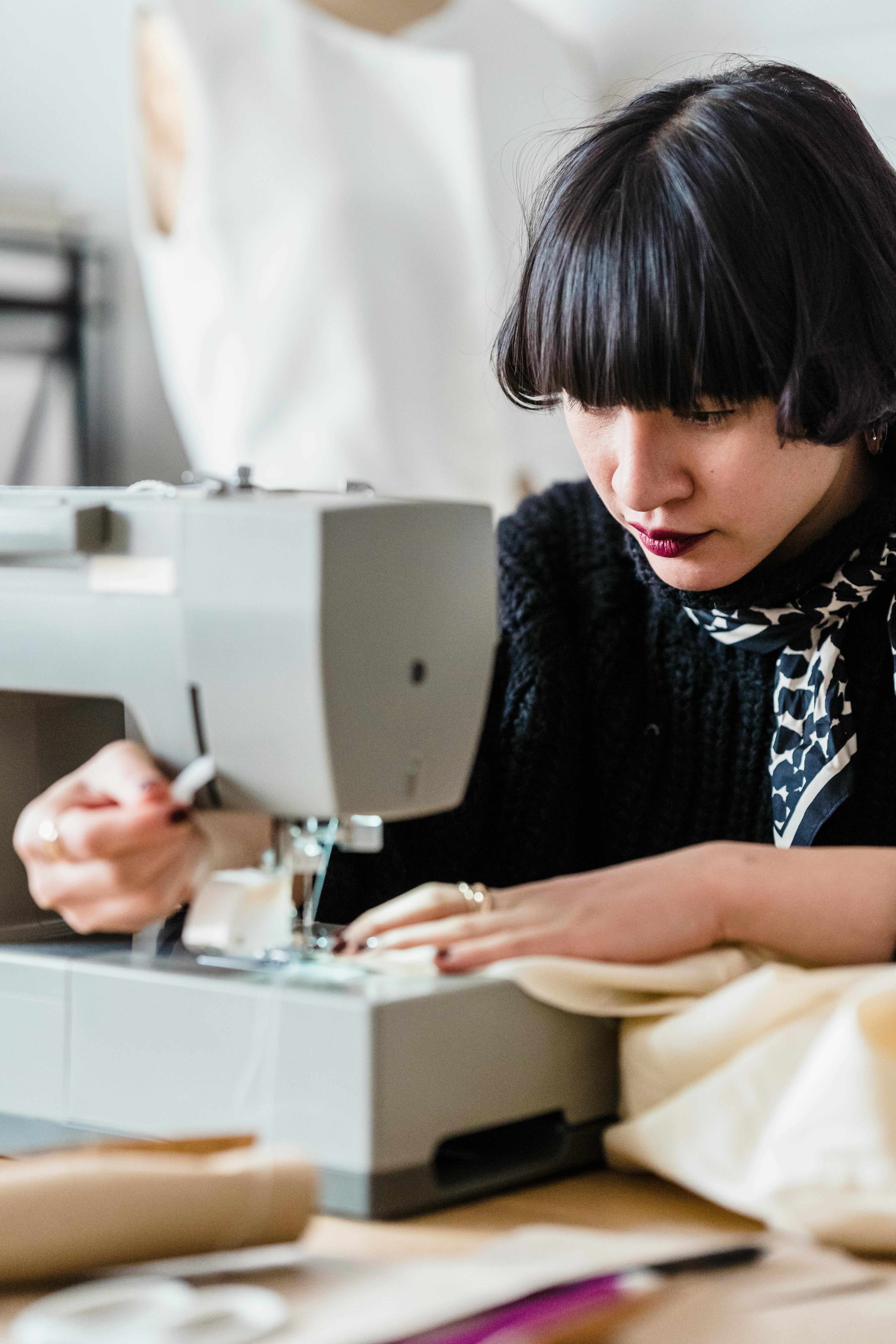 asian seamstress sewing fabric in atelier