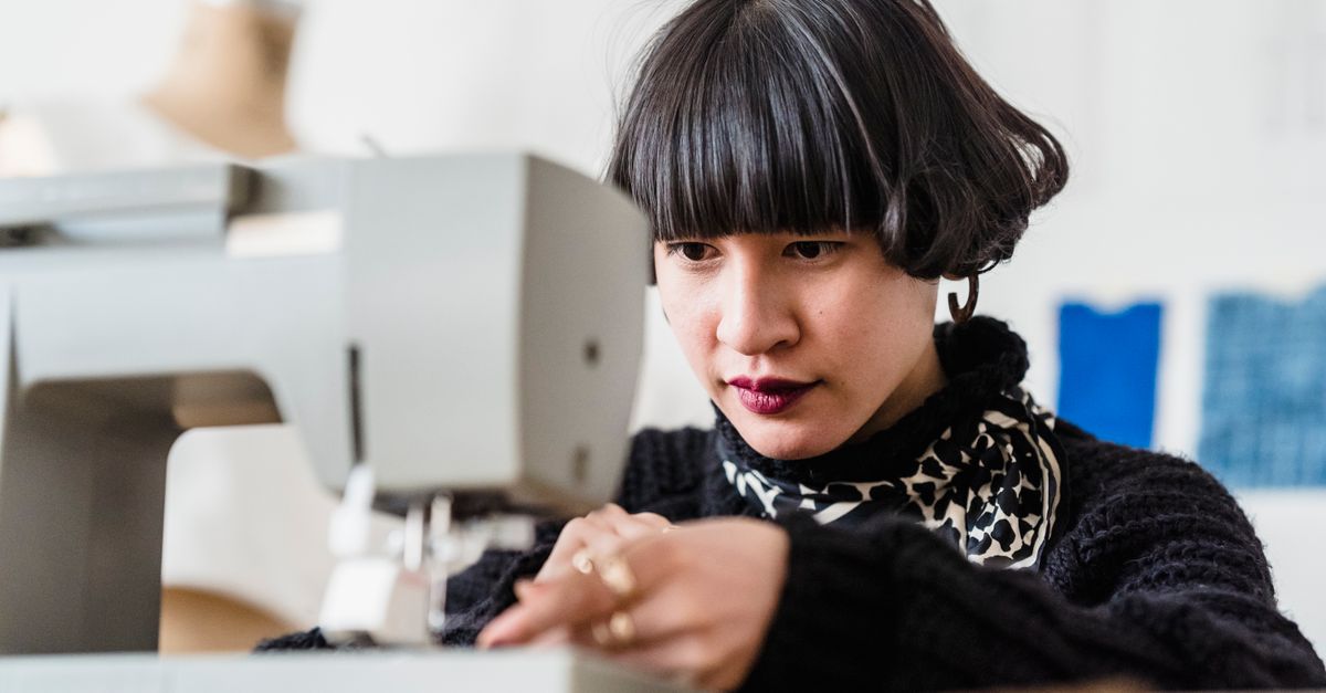 Focused Asian tailor threading sewing machine · Free Stock Photo