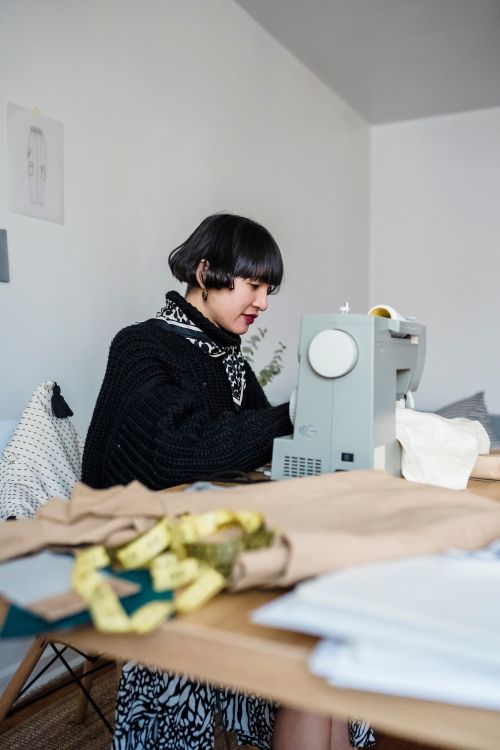 Dressmaker at the table with fabric and sewing machine
