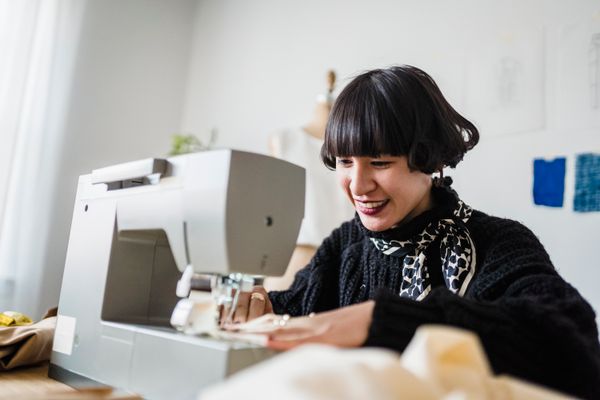 A woman smiling as she works at a sewing machine