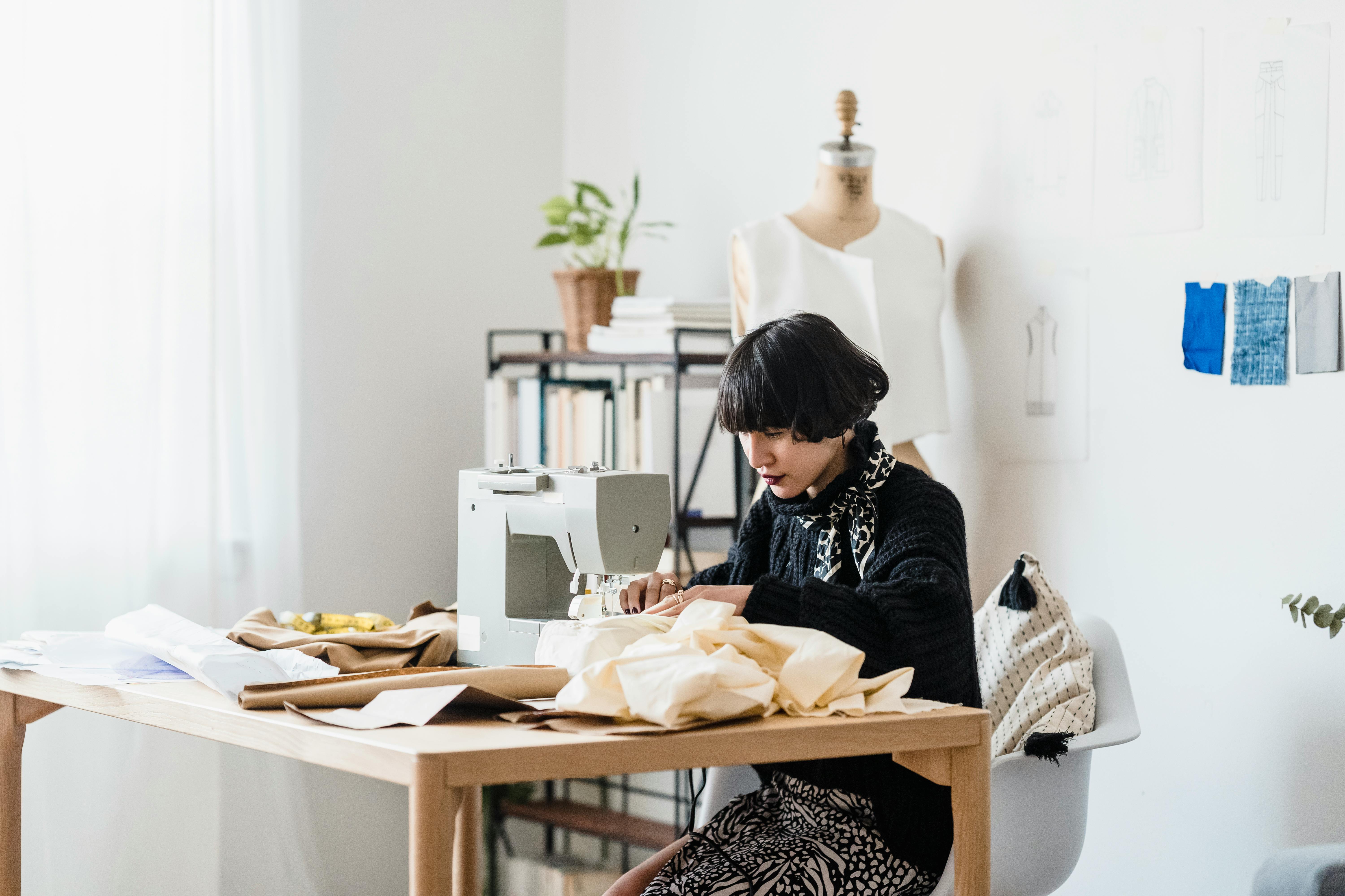 concentrated young asian seamstress working on sewing machine while creating new dress