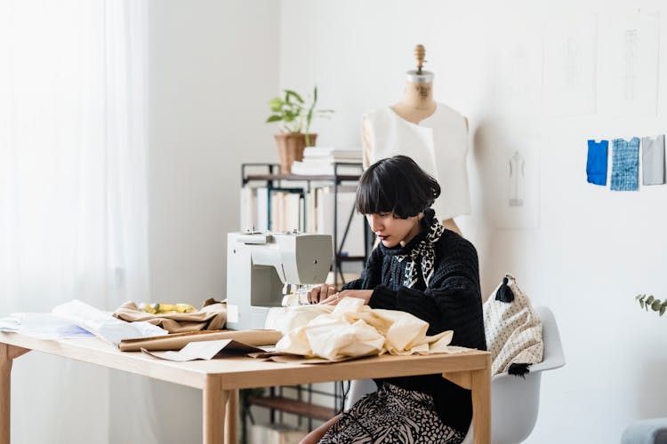 Concentrated Young Asian Seamstress Working On Sewing Machine While Creating New Dress