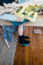 From above of crop unrecognizable female tailor pushing foot pedal while working on sewing machine sitting at wooden table in atelier