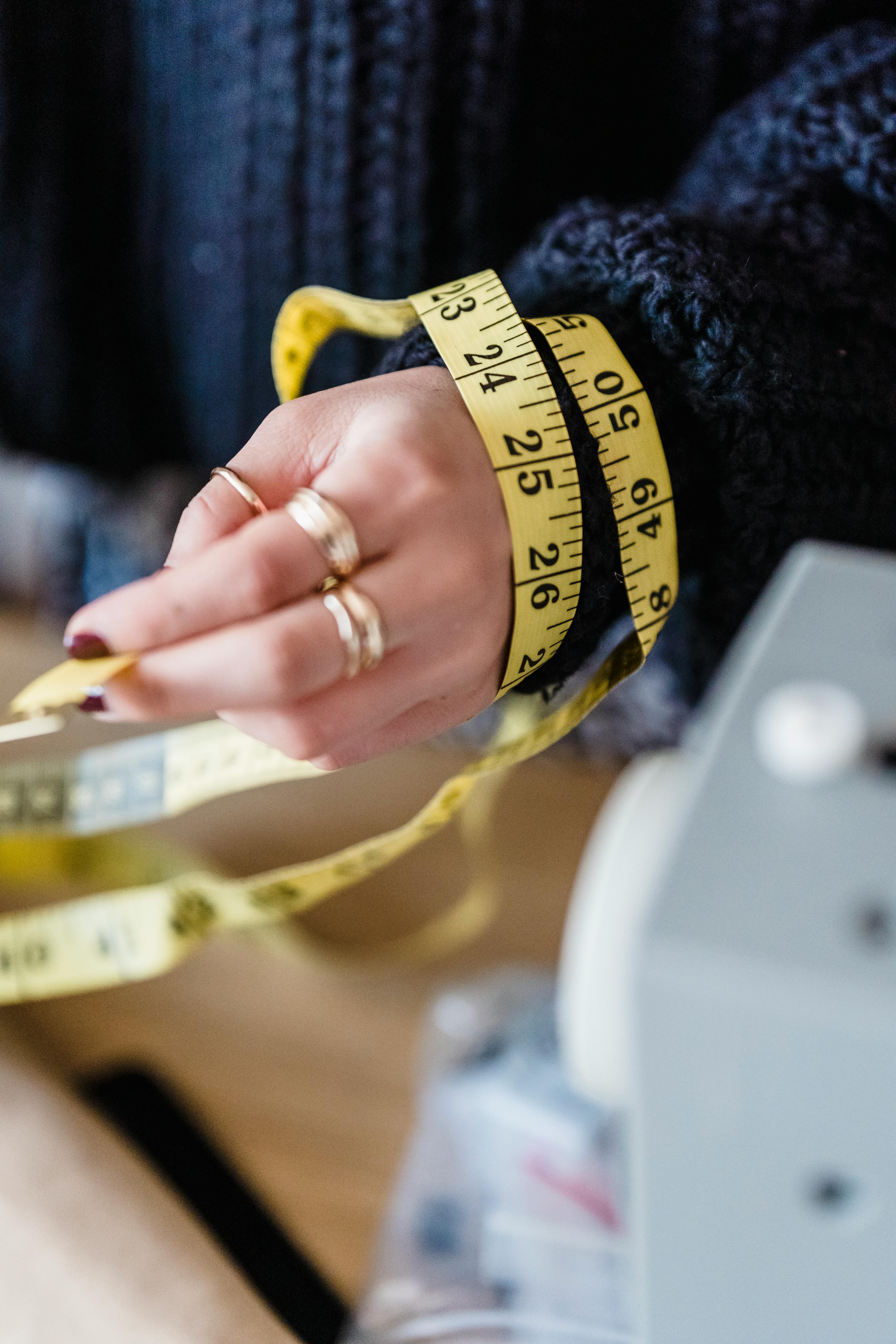 tailor in dark blue sweater with measuring tape