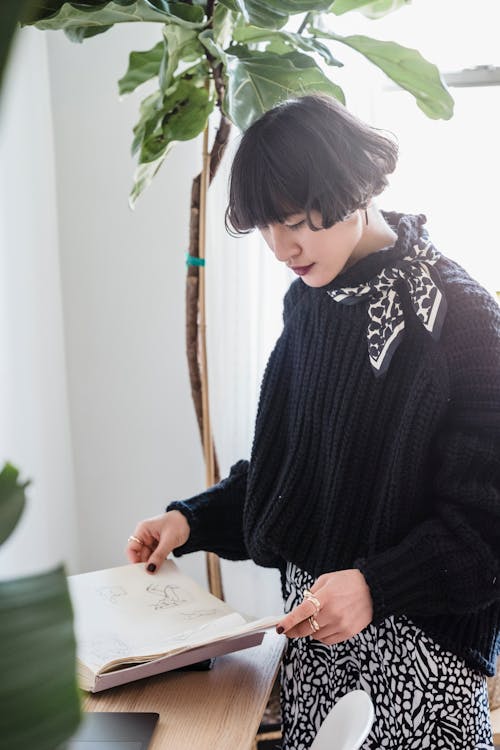 Fashionable woman in stylish clothes looking through sketches